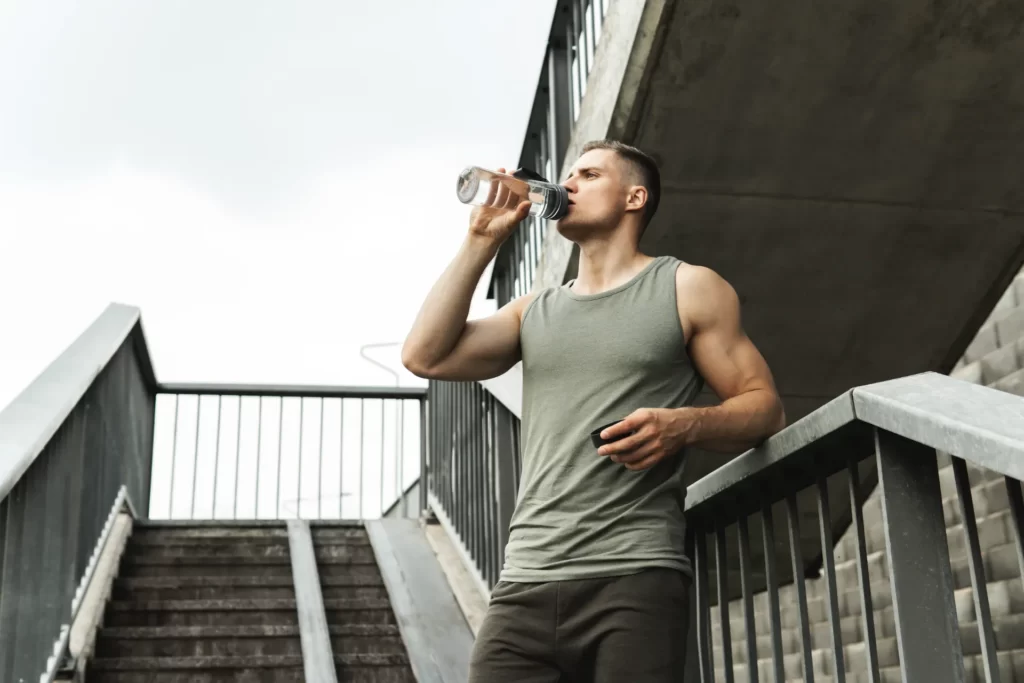 man drinking water after workout in urban setting utc